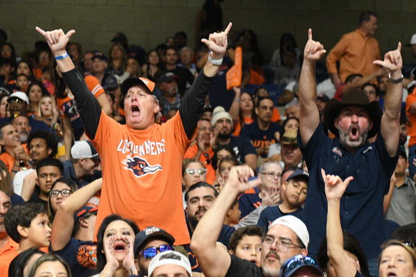 Dads cheering with hand symbol up in air at football game